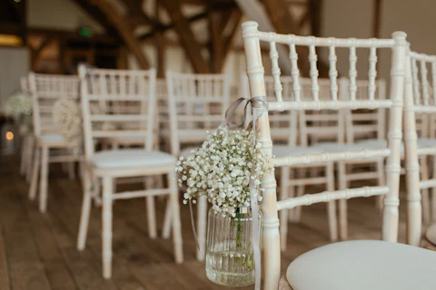 Jar of baby's breath hung on a white ceremony chair along the aisle