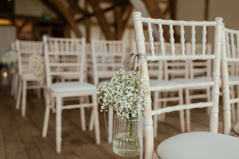 Jar of baby's breath hung on a white ceremony chair along the aisle
