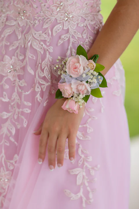 Blush rose wrist corsage worn with a pink lace formal dress