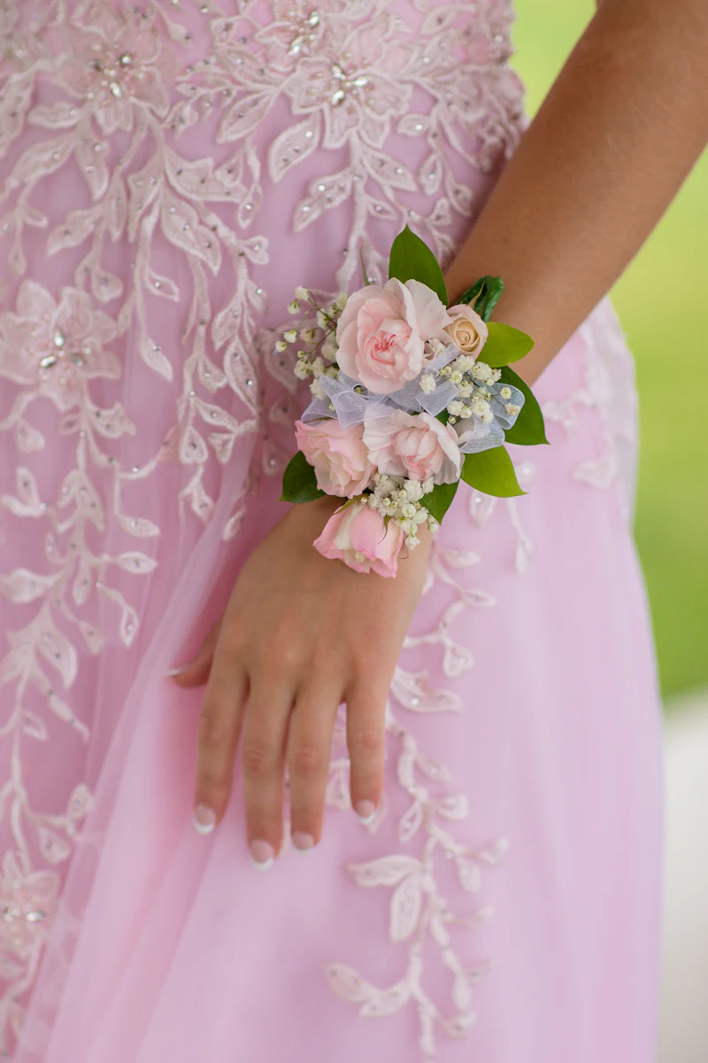 Blush rose wrist corsage worn with a pink lace formal dress
