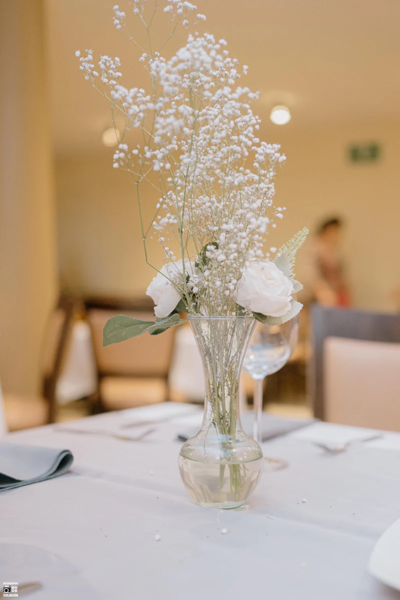 Bud vase of baby's breath and white roses on a party table