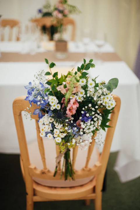 Wildflower posy tied to the back of a wooden reception chair