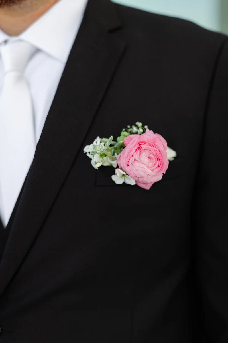 Pink rose boutonniere on a black suit lapel