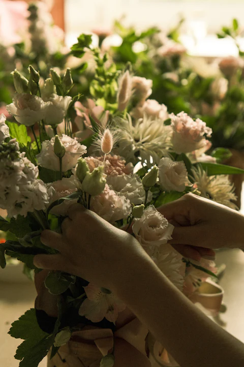 Hands arranging pastel flowers in a basket