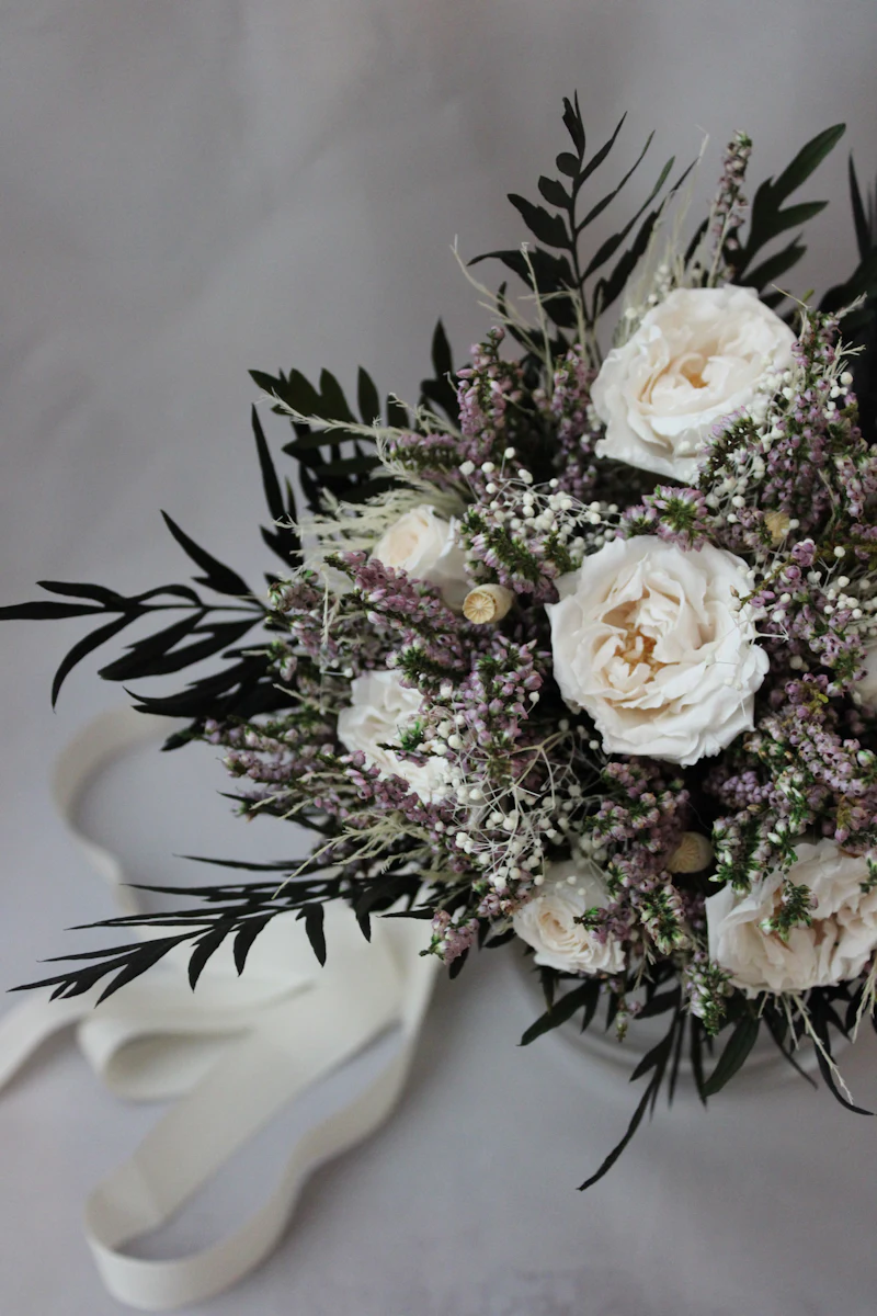 Bouquet of white roses, heather and dark greenery with ribbon