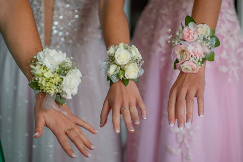 Three wrist corsages in white, green and blush worn with formal dresses